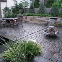waterfall flows from retaining wall through rill to koi pond